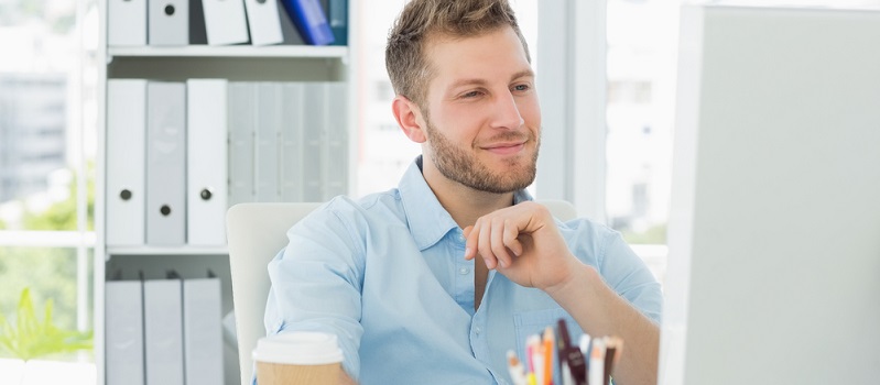 Smiling man working at his desk in creative office-landing page